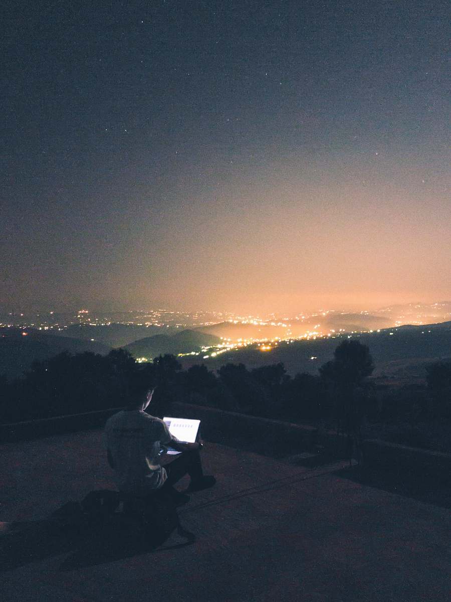 This captivating photograph features a man sitting on a rooftop in Ait Bouadou, Tizi Ouzou, gazing intently at his laptop while the enchanting night sky unfolds above him. The image beautifully captures a moment of contemplation and connection with technology amidst the serene backdrop of the cosmos. Ideal for use in articles on technology, mindfulness, or lifestyle, this photo conveys a sense of wonder and possibility, making it perfect for websites, blogs, and social media content.